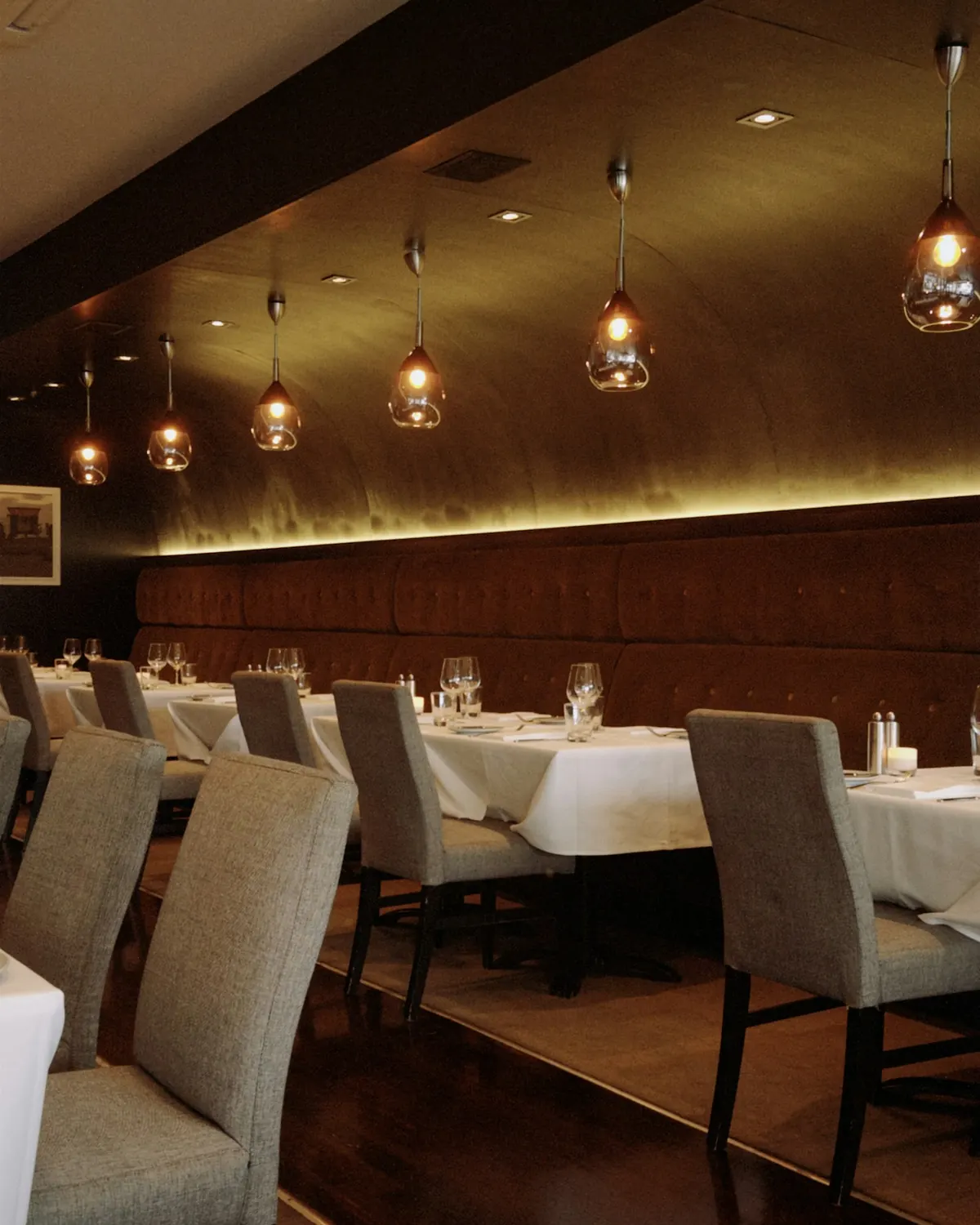 Een restaurant in de avond: gedekte tafels met wit linnen onder warme hanglampen