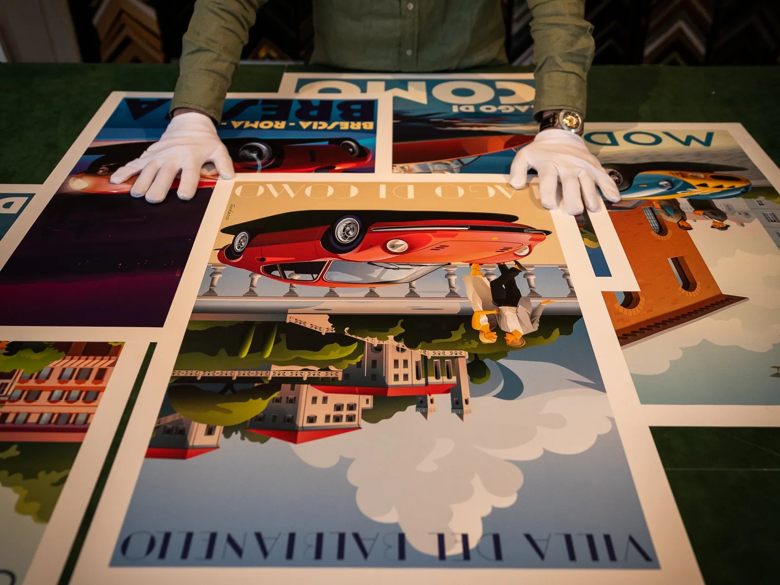 Handen in witte handschoenen leggen affiches van Ferdasco uit op tafel