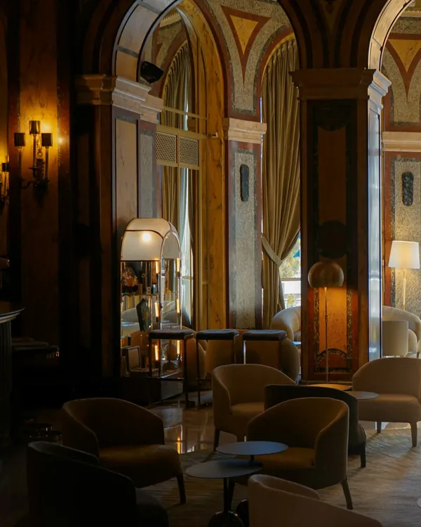 Een hotellounge met marmeren zuilen, fauteuils en warme staande lampen