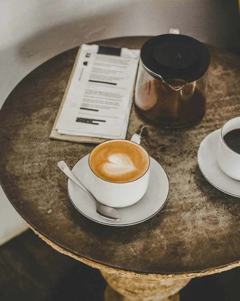 Twee koppen koffie en een vel papier met aantekeningen op een ronde cafétafel